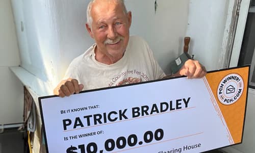 Patrick Bradley holding a $10,000 Publishers Clearing House winner check